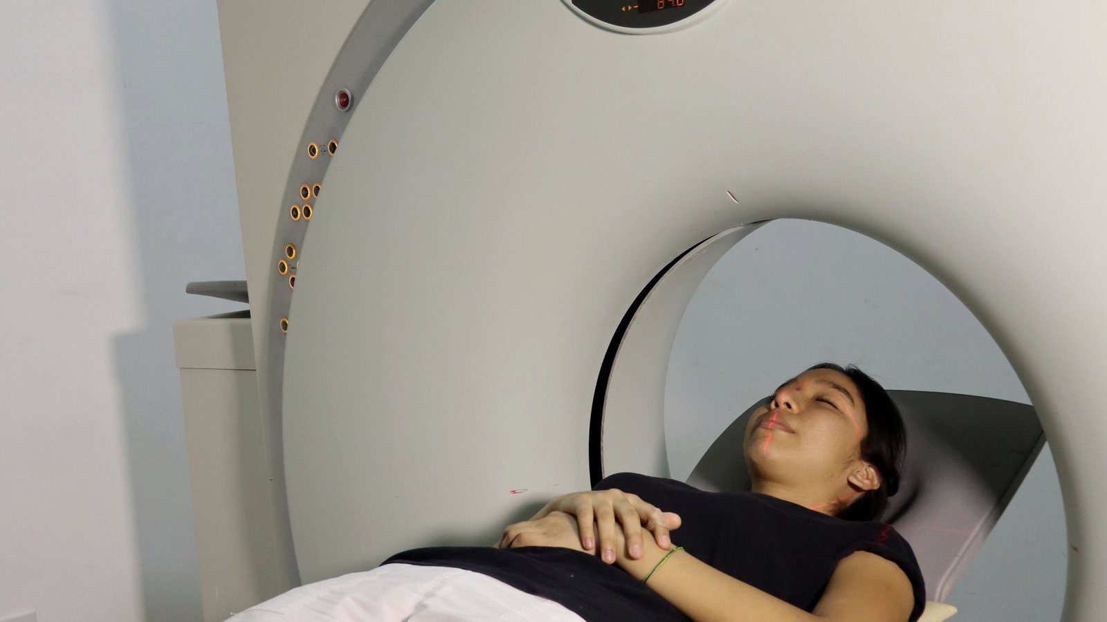 A patient lies inside a medical imaging scanner in a clinical room.